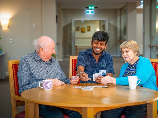 BAPTCARE ABBEY GARDENS residents and staff member playing cards together