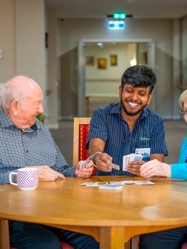 BAPTCARE ABBEY GARDENS residents and staff member playing cards together