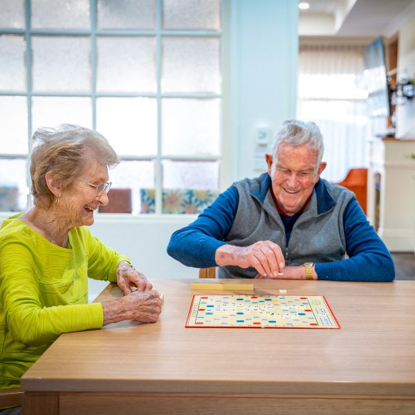 BAPTCARE AMBERLEA Resident friends playing scrabble at a table in the lounge area