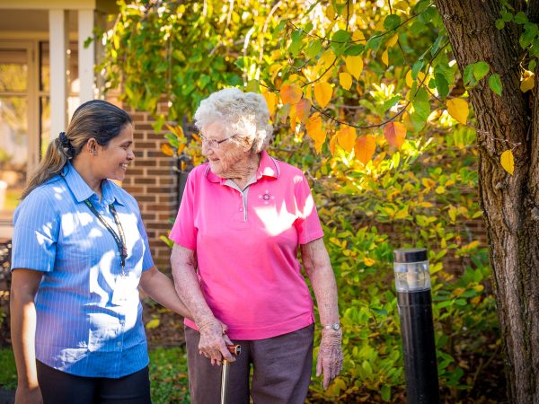 BAPTCARE AMBERLEA Residents and staff member going for a walk and chatting outside in the courtyard gardens