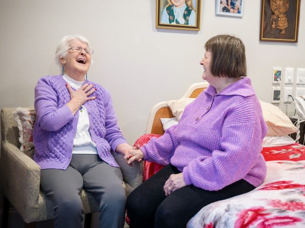 BAPTCARE BROOKVIEW Resident friends in one of their bedrooms chatting and laughing heartily