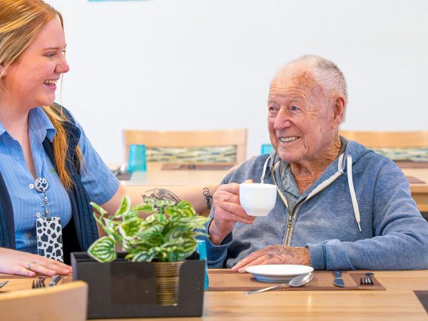 BAPTCARE COASTHAVEN Resident chatting with a staff member in the dining room over a coffee