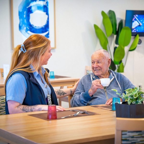 BAPTCARE COASTHAVEN Resident chatting with a staff member in the dining room over a coffee