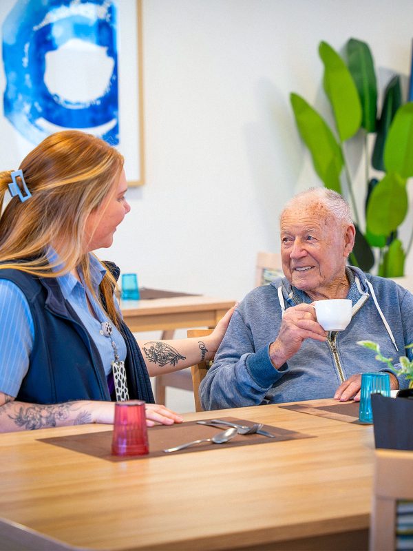 BAPTCARE COASTHAVEN Resident chatting with a staff member in the dining room over a coffee