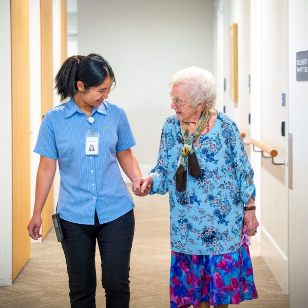 BAPTCARE COASTHAVEN Resident chatting with a staff member walking in a corridor