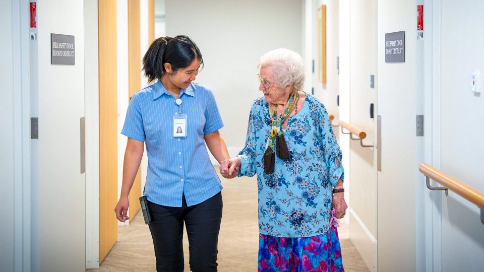 BAPTCARE COASTHAVEN Resident chatting with a staff member walking in a corridor