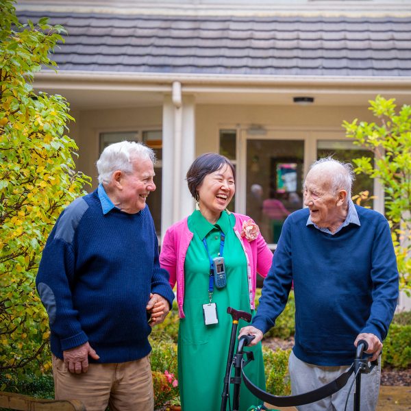 BAPTCARE HEDLEY SUTTON Resident friends taking a walk in the courtyard with a staff member having a joke with them