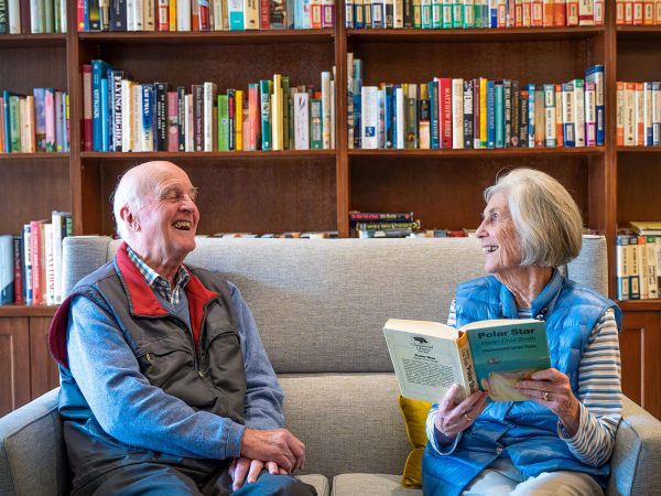 BAPTCARE HEDLEY SUTTON Resident couple reading and chatting in the library