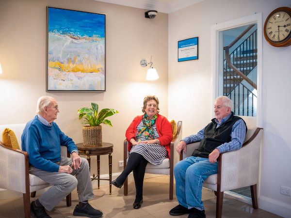 BAPTCARE HEDLEY SUTTON Resident friendship group of three chatting together quietly in a small nook in the lounge area
