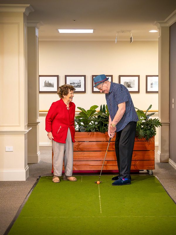 BAPTCARE HERITAGE MANOR Resident friends on the putting golf green inside in the activities area