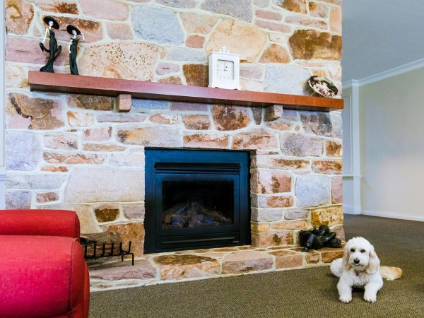 BAPTCARE HERITAGE MANOR large fireplace with resident friendly dog