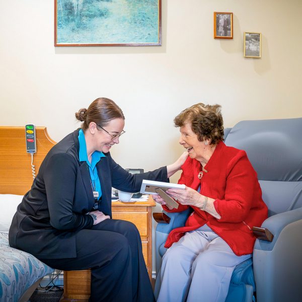 BAPTCARE HERITAGE MANOR Resident with staff member having a chat and laugh in her room