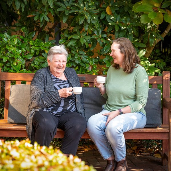 BAPTCARE KARANA Resident mother and daughter in courtyard garden tea and laughter