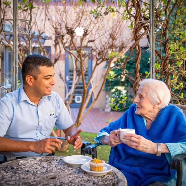 BAPTCARE KARANA Resident with staff member sharing conversation and a cupcake with tea