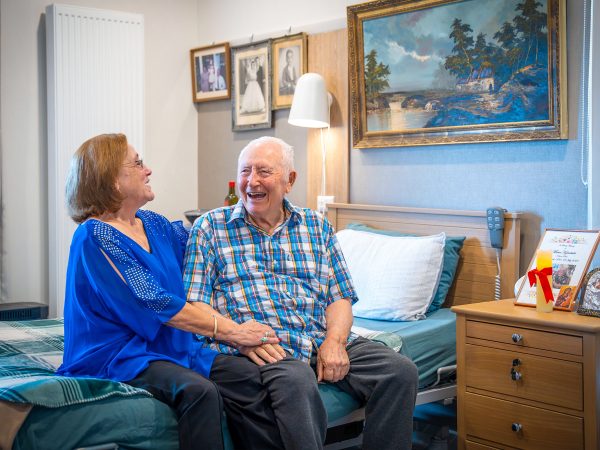 BAPTCARE WATTLE GROVE resident with his daughter in his room sharing a hearty laugh