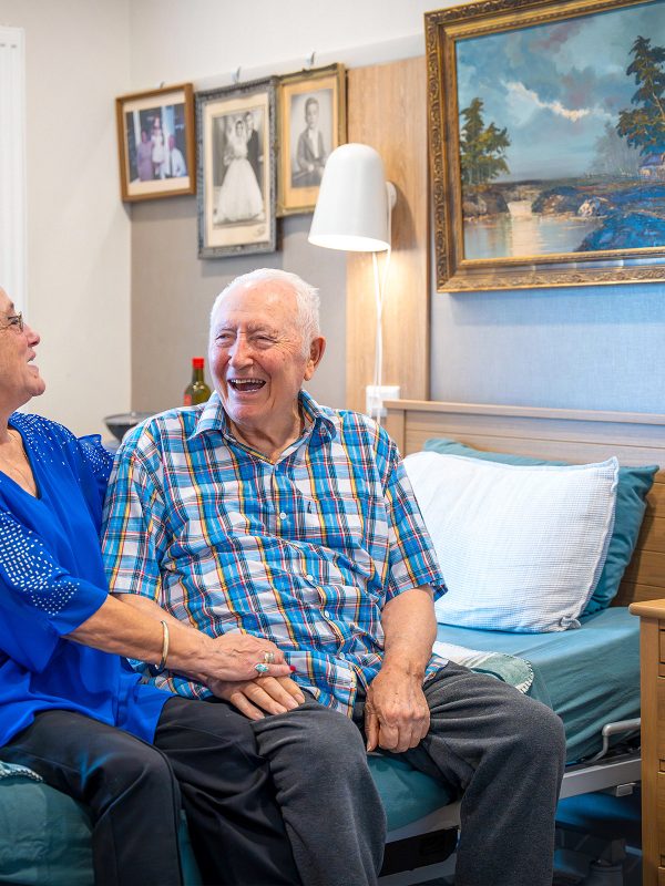 BAPTCARE WATTLE GROVE resident with his daughter in his room sharing a hearty laugh