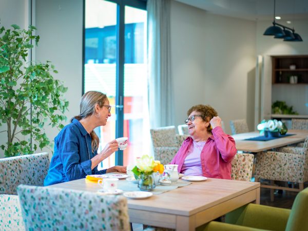 BAPTCARE WATTLE GROVE Resident mother and daughter in cafe sharing a cheerful moment over tea