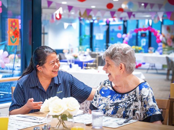 BAPTCARE Wyndham Lodge staff member chatting with resident at a celebration