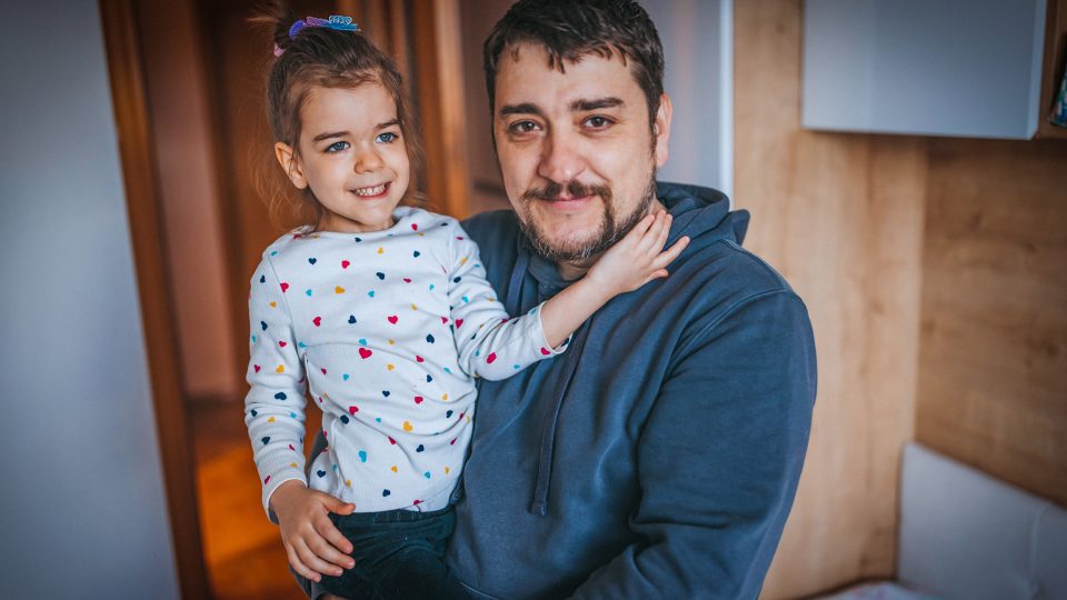 FAMILY COMMUNITY Young dad hugging young daughter staring at the camera both smiling