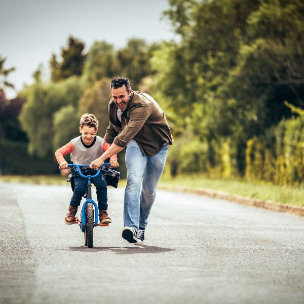 Male foster carer helping a young boy in his care learn to ride a bike