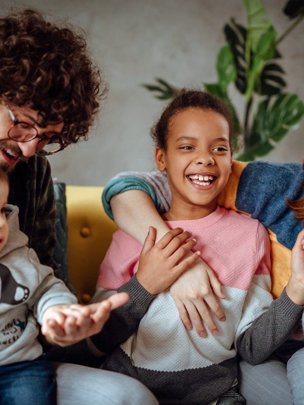 Young male female couple foster carers joking with a twelve year old girl brought into their care also with their own young son