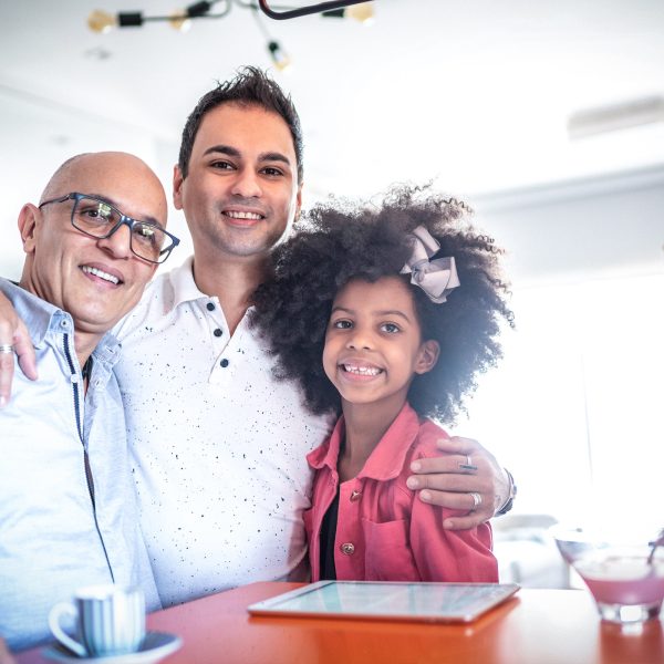 Same sex older male couple foster carers looking after a young girl in their home