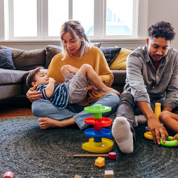 Young male female multicultural couple foster carers playing with two young siblings brought into their care