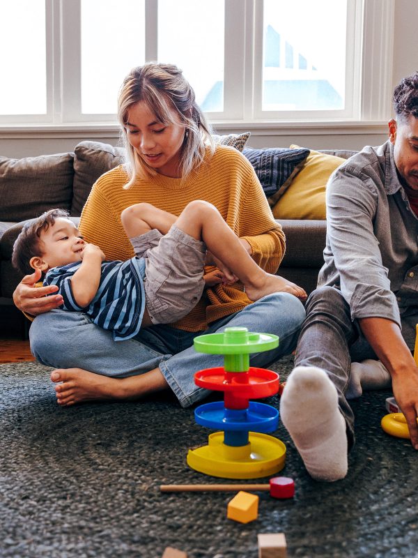 Young male female multicultural couple foster carers playing with two young siblings brought into their care