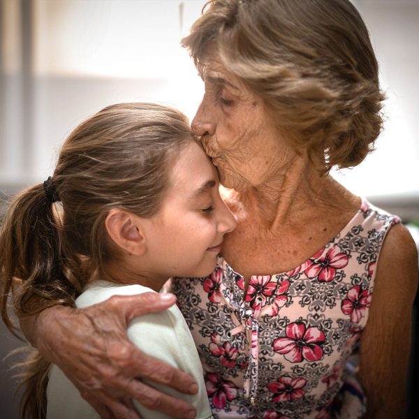 KINSHIP CARE grandmother giving her granddaughter a loving hug and a kiss on the forehead