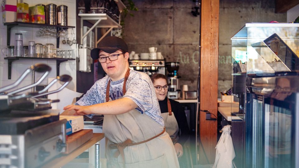 DISABILITY young adult male with Downs syndrome working in a cafe