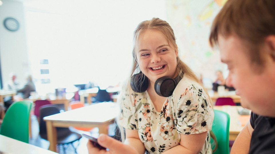 DISABILITY young adult female with Downs syndrome chatting with her male friend in a cafe over lunch