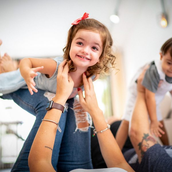 DISABILITY mum and dad playing with two kids, one with Downs syndrome throwing them into the air both are smiling with the joy of it