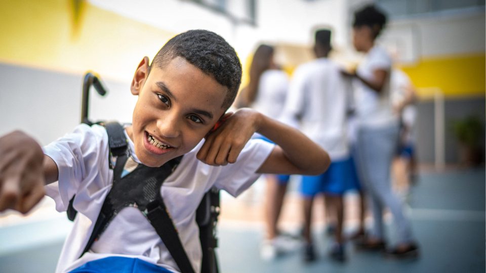 DISABILITY a teenage boy wheelchair bound with cerebral palsy at school smiling at camera