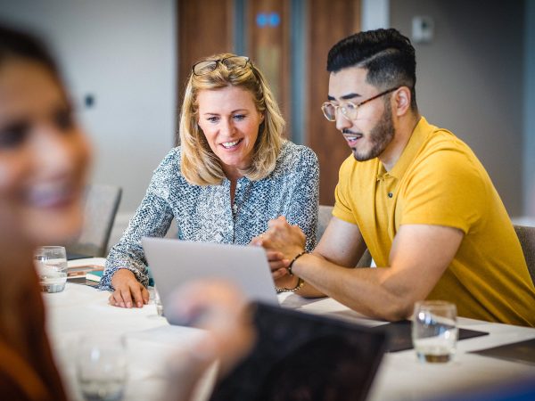 MENTAL HEALTH co workers female and male discussing work while looking at a laptop