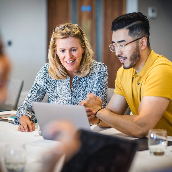 MENTAL HEALTH co workers female and male discussing work while looking at a laptop