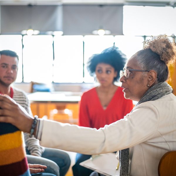 MENTAL HEALTH Woman leading the Horizons group therapy compassion with hand on shoulder of an older male as she listens intently