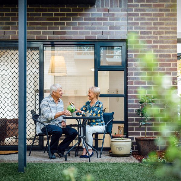 Resident outside her apartment with partner at Westhaven pouring tea