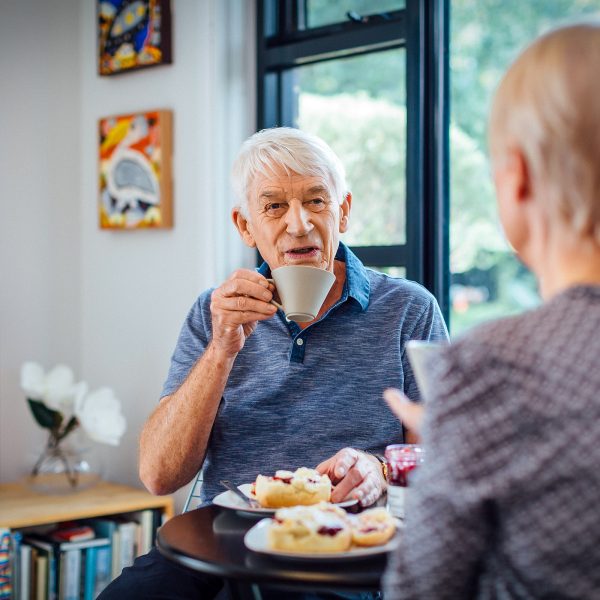 Resident inside his apartment at Westhaven with his partner enjoying tea and scones