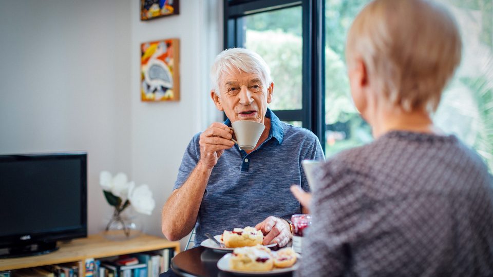 Resident inside his apartment at Westhaven with his partner enjoying tea and scones