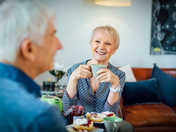 Resident inside her apartment at Westhaven with her partner enjoying tea and scones