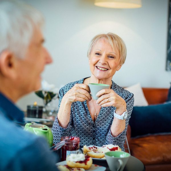 Resident inside her apartment at Westhaven with her partner enjoying tea and scones