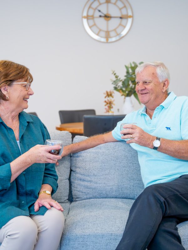 Retirement Living residents in their apartment enjoying a drink on their couch