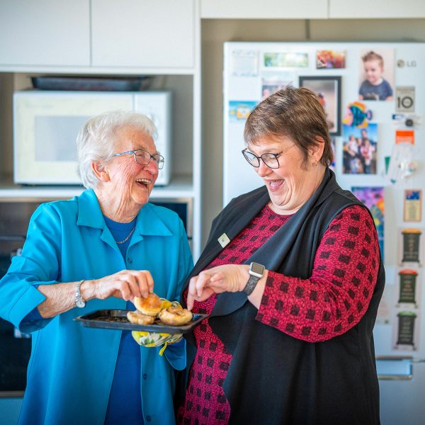 Resident and Retirement Living Manager Tania in her kitchen enjoying a laugh with a snack at Karingal Retirement Living