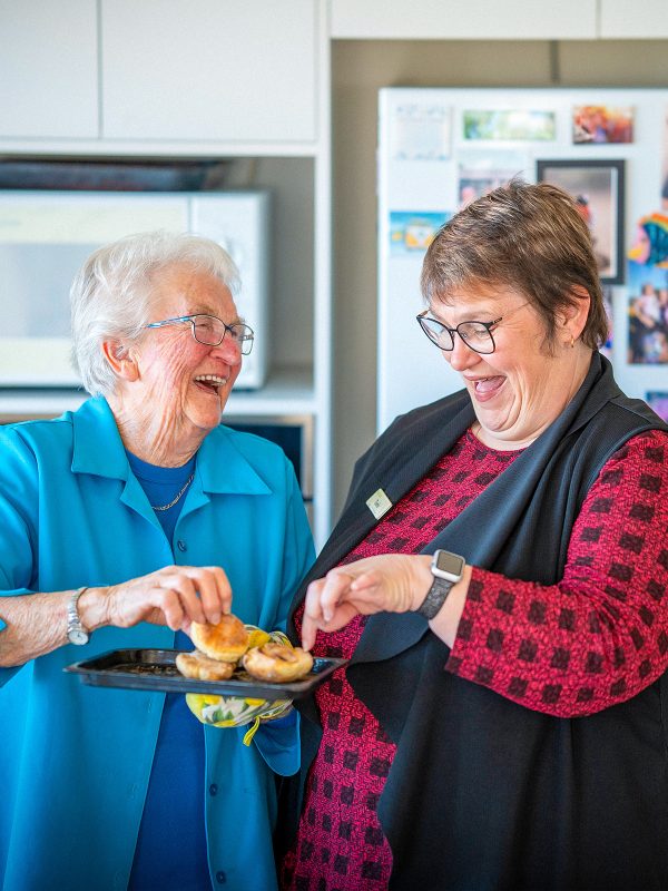 Resident and Retirement Living Manager Tania in her kitchen enjoying a laugh with a snack at Karingal Retirement Living