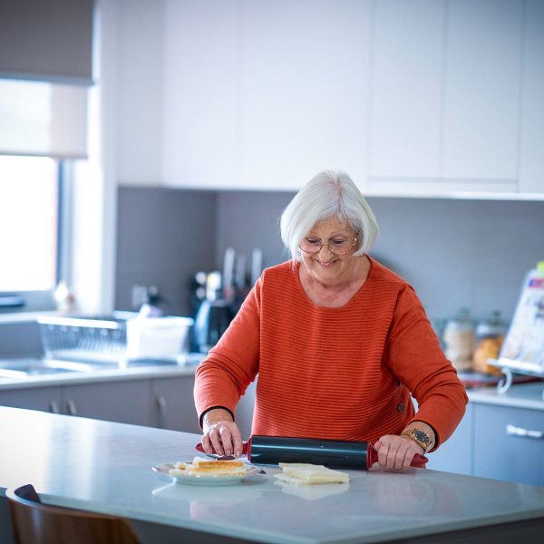 Resident in kitchen of her villa at Karingal Retirement Living rolling dough