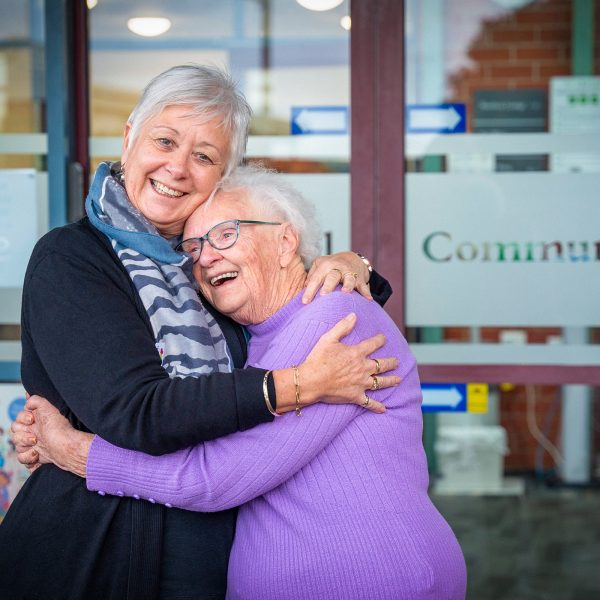 BAPTCARE KARINGAL Resident mother and daughter outside entrance laughter and a great big hug full of joy