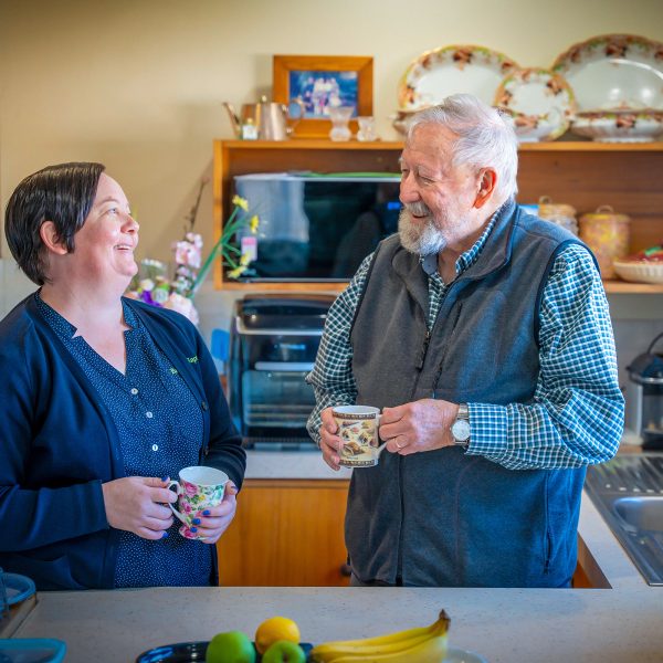 HOME CARE staff member with a customer at their home having a chat over tea while doing a wellbeing check