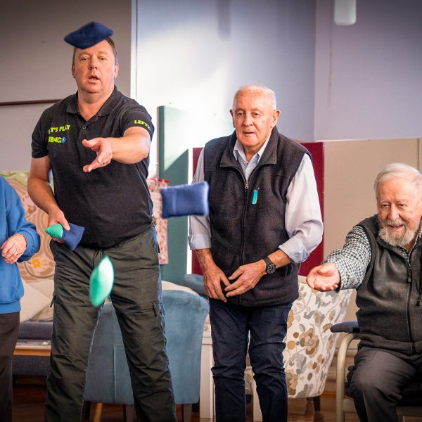 HOME CARE staff member playing a Bean Bag Bucket game with Home Care Package customers at Orana Social Activities and Respite Centre