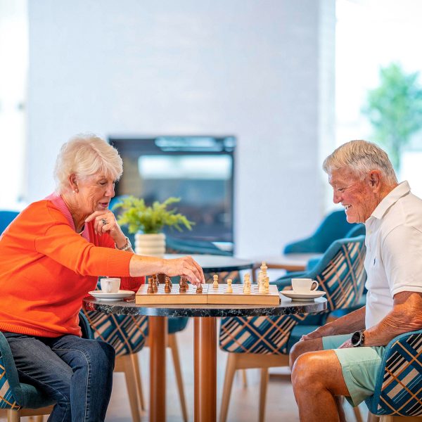 Residents at Peninsula View Retirement Living apartments in the residents lounge enjoying a game of chess