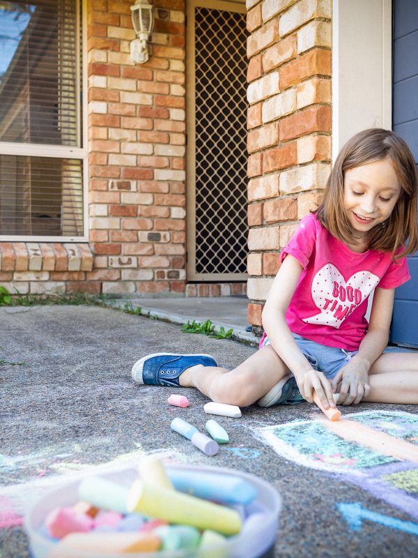 A young girl, an affordable housing resident standing outside her rental home supplied by Baptcare